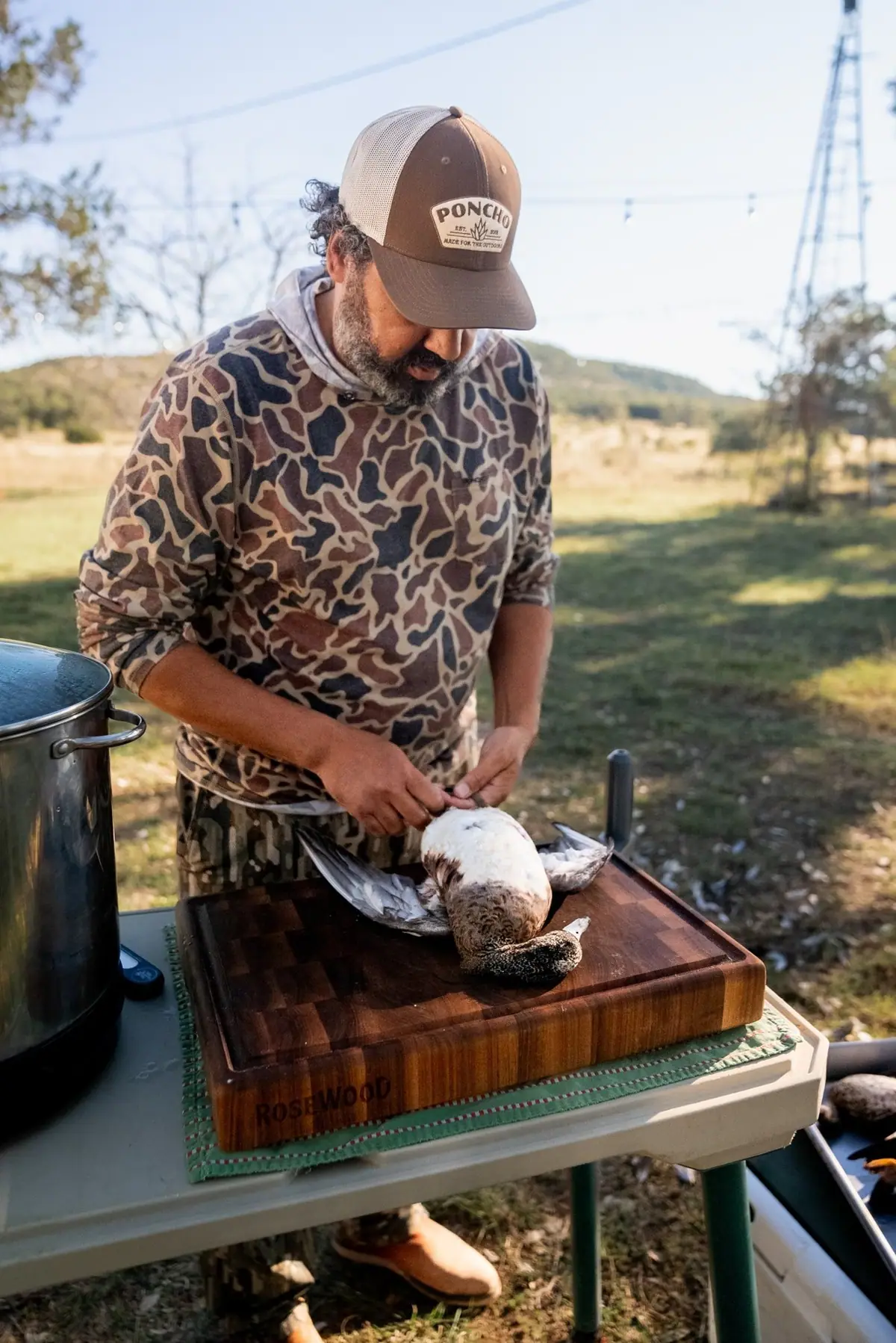 Josh Crumpton breaking down wild game at an outdoor camp kitchen
